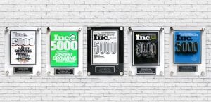 five INC 5000 Plaques on a white brick wall