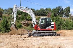 Man drives Takeuchi TB2150 Excavator over work site