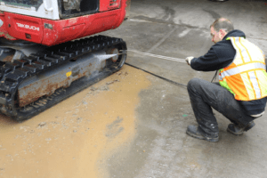 Excavator track maintenance with power washer