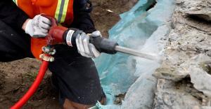 Construction worker using rock drill to break rock